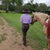 woman in purple shirt waling with a horse