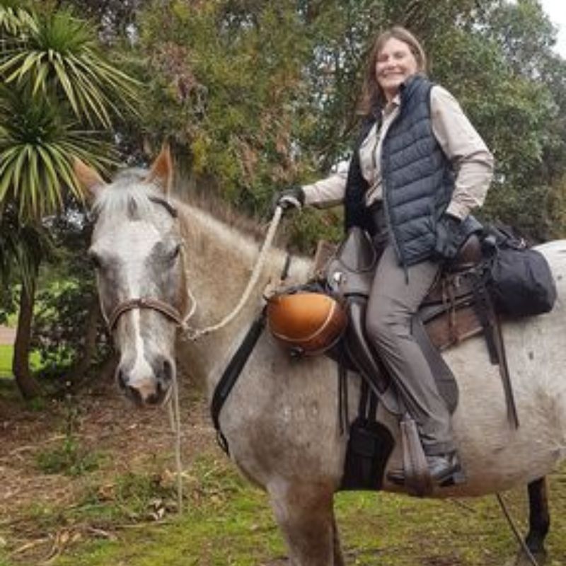 woman in vest riding a horse