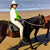 woman riding a horse beside a beach