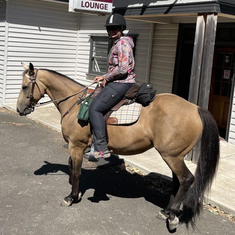 woman riding a horse in front of a store