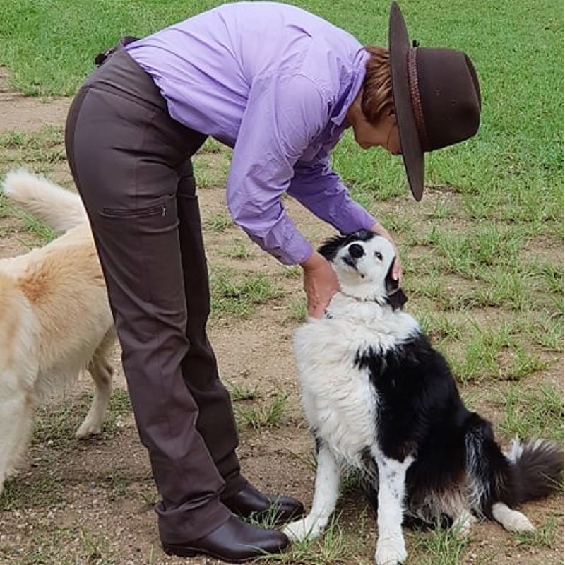 women standing with a black and white dog