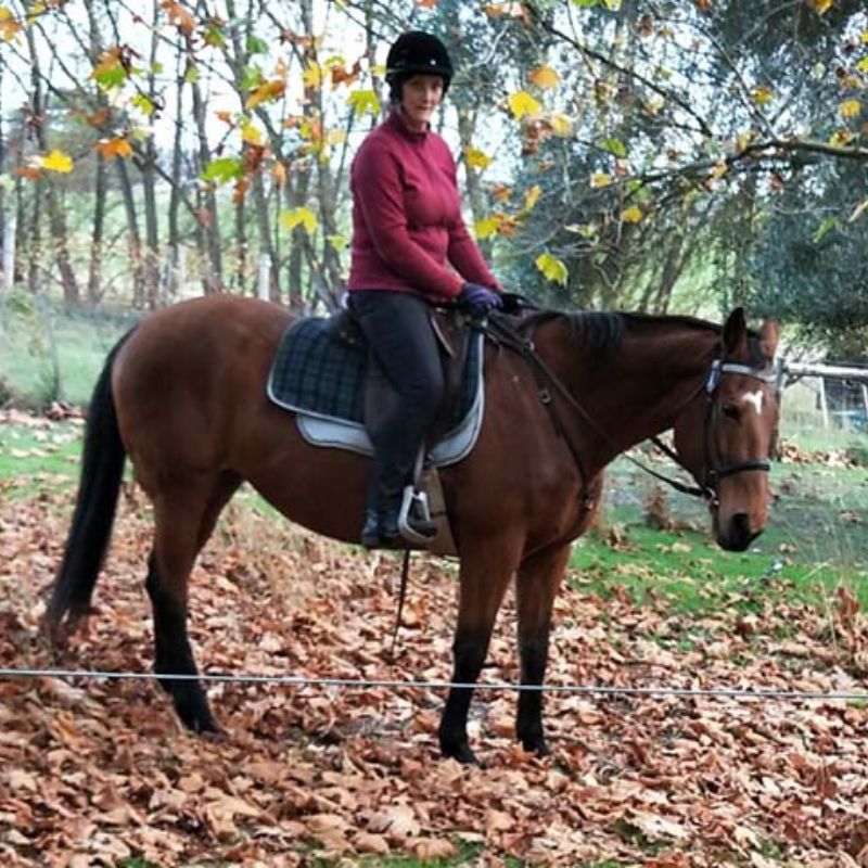 women in red riding a brown horse