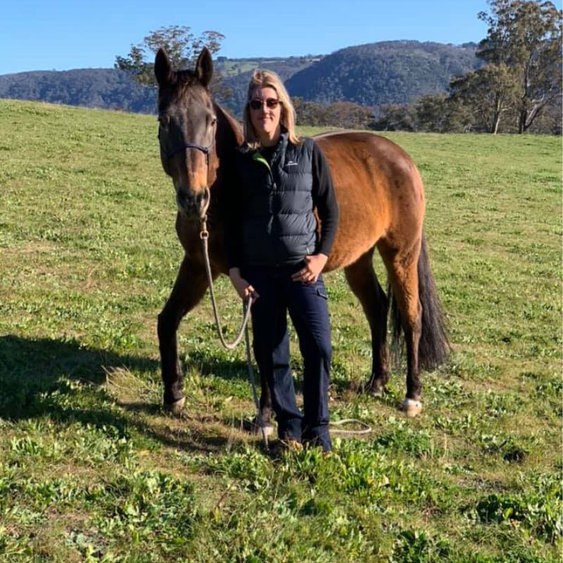woman in sunglasses standing in front of a horse