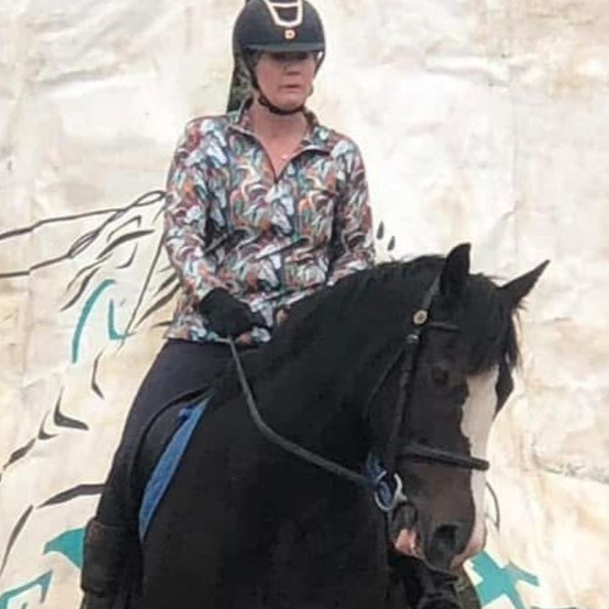 woman riding in a horse wearing a horse riding shirt in aurora print
