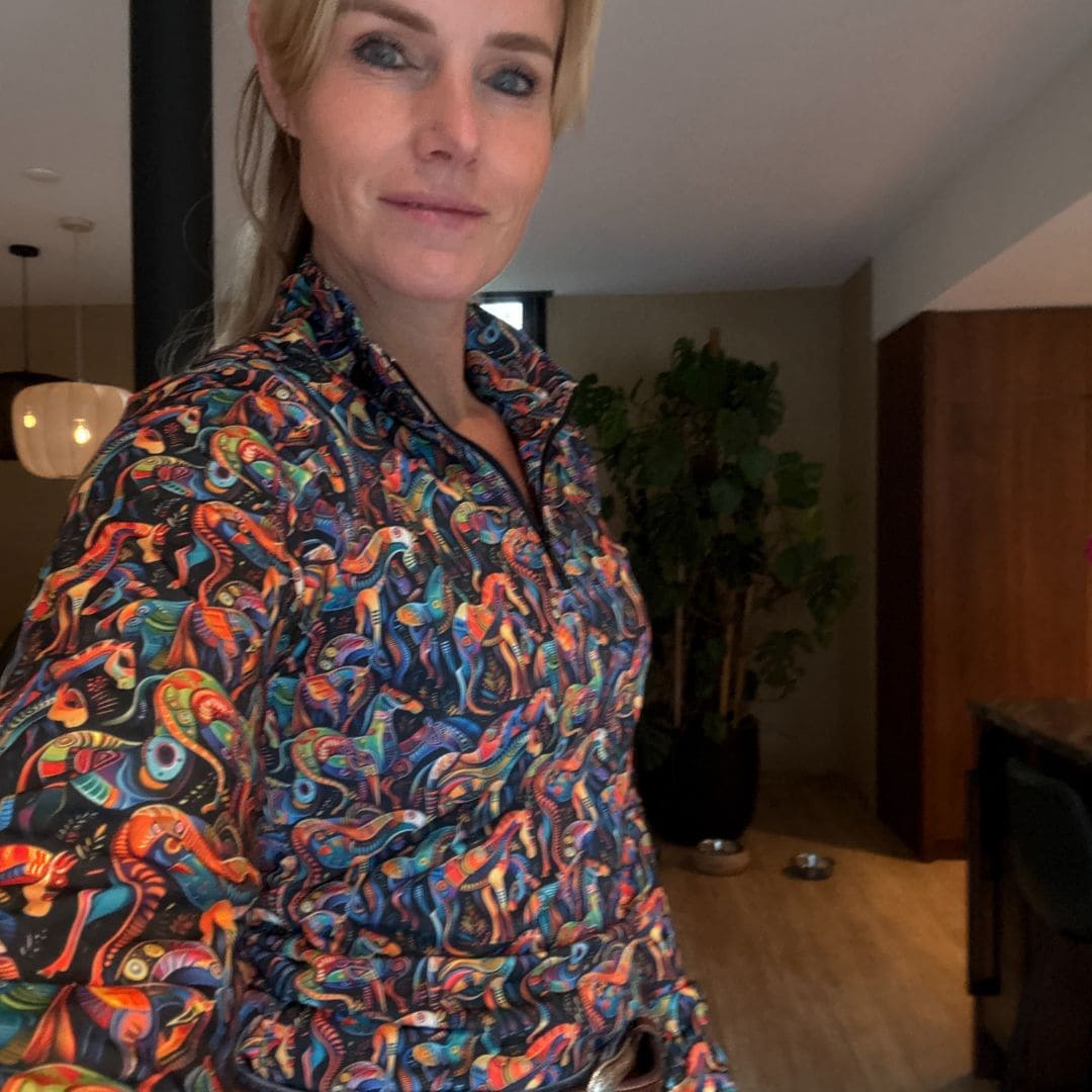 Woman wearing a colorful kaleidoscope patterned shirt from Ride Proud in an indoor setting