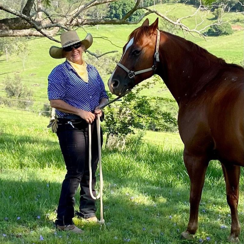 woman wearing a light brown hat holding the horse