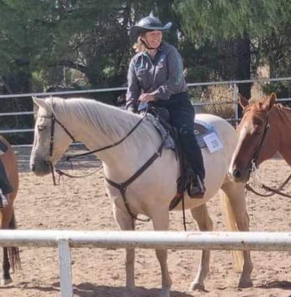 woman riding a white horse in a horizon horse riding pants