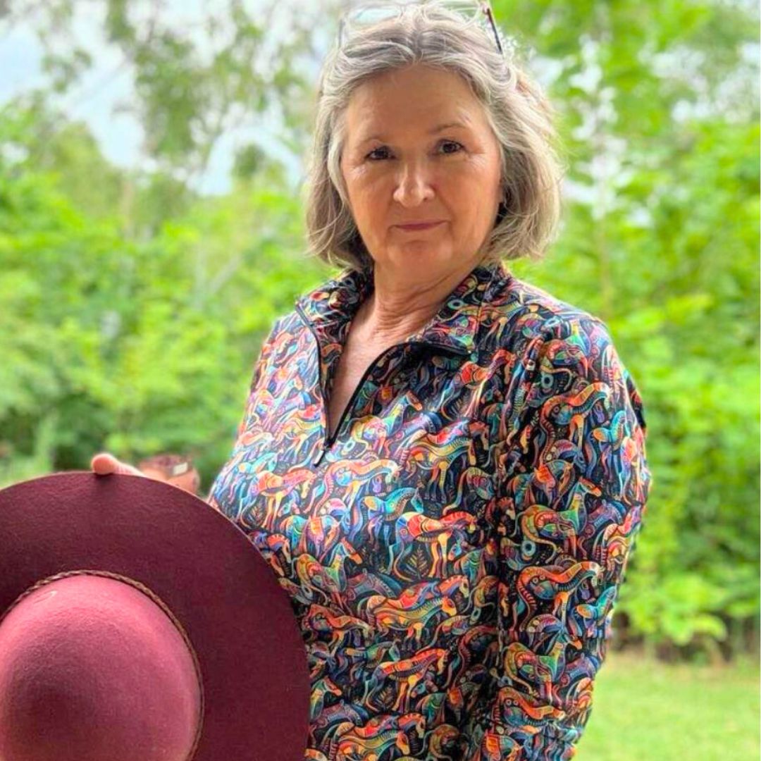 women in Ride Proud Kaleidoscope Riding Shirt long sleeve holding a red hat