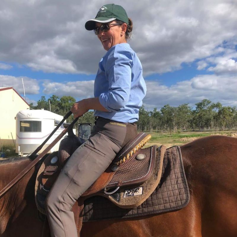 woman in green cap riding a horse