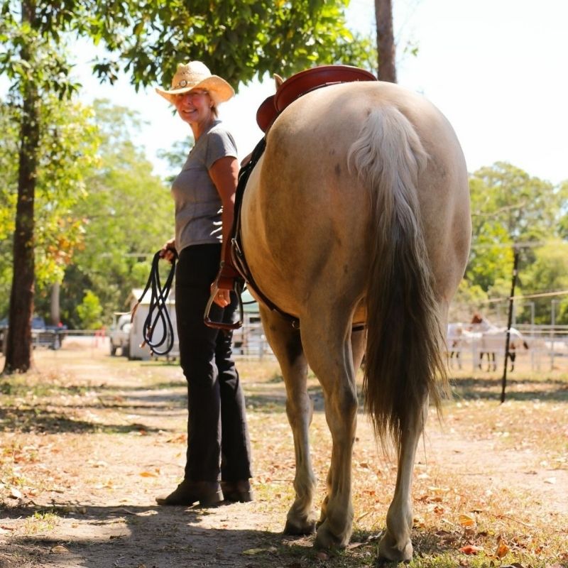 woman in equitation standing beside her horse